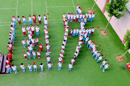 济南市历城区北全福小学的百余名学生手拿小国旗,摆出国庆字样
